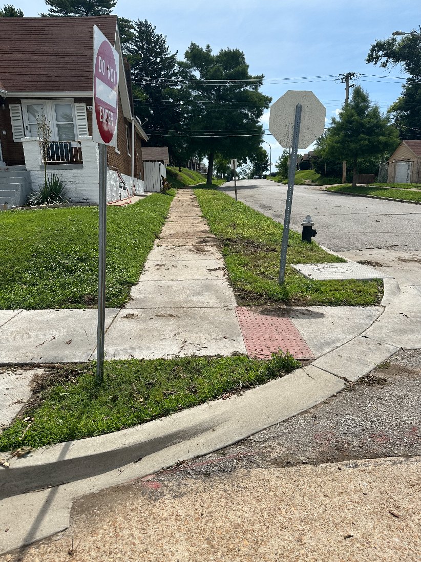 The same curb and sidewalk fully cleared of logs and brush